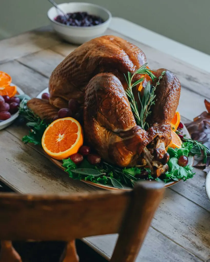 Festlich gebratene Weihnachtsgans auf Servierplatte mit Orangen, Kräutern und Beilagen – klassisches Weihnachtsessen